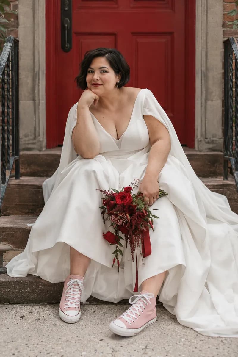Ilustración creada con IA: novia sentada en un escalón con el codo en la rodilla, ramo en la mano y zapatillas rosadas