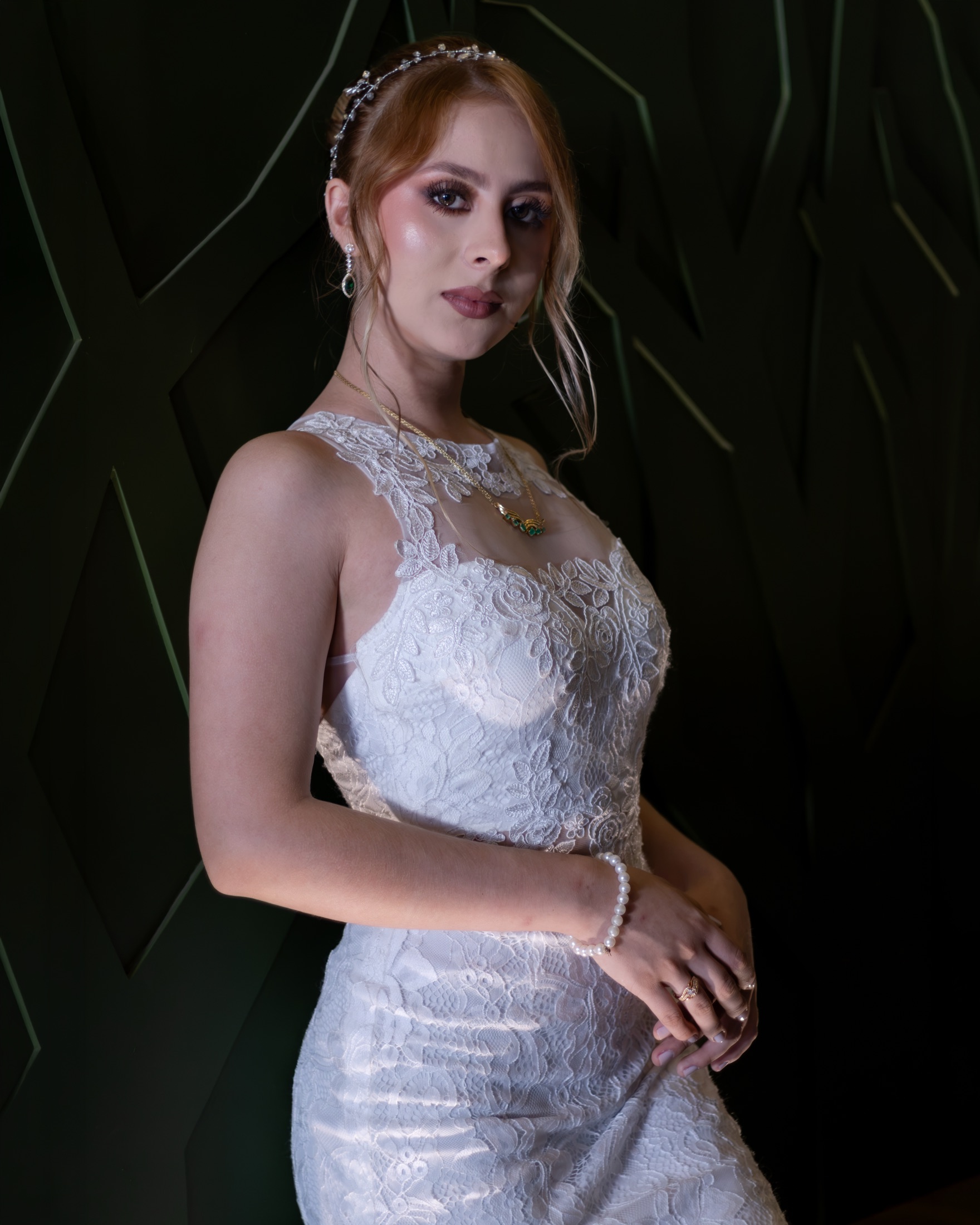 Novia apoyada en una pared oscura con mirada lateral