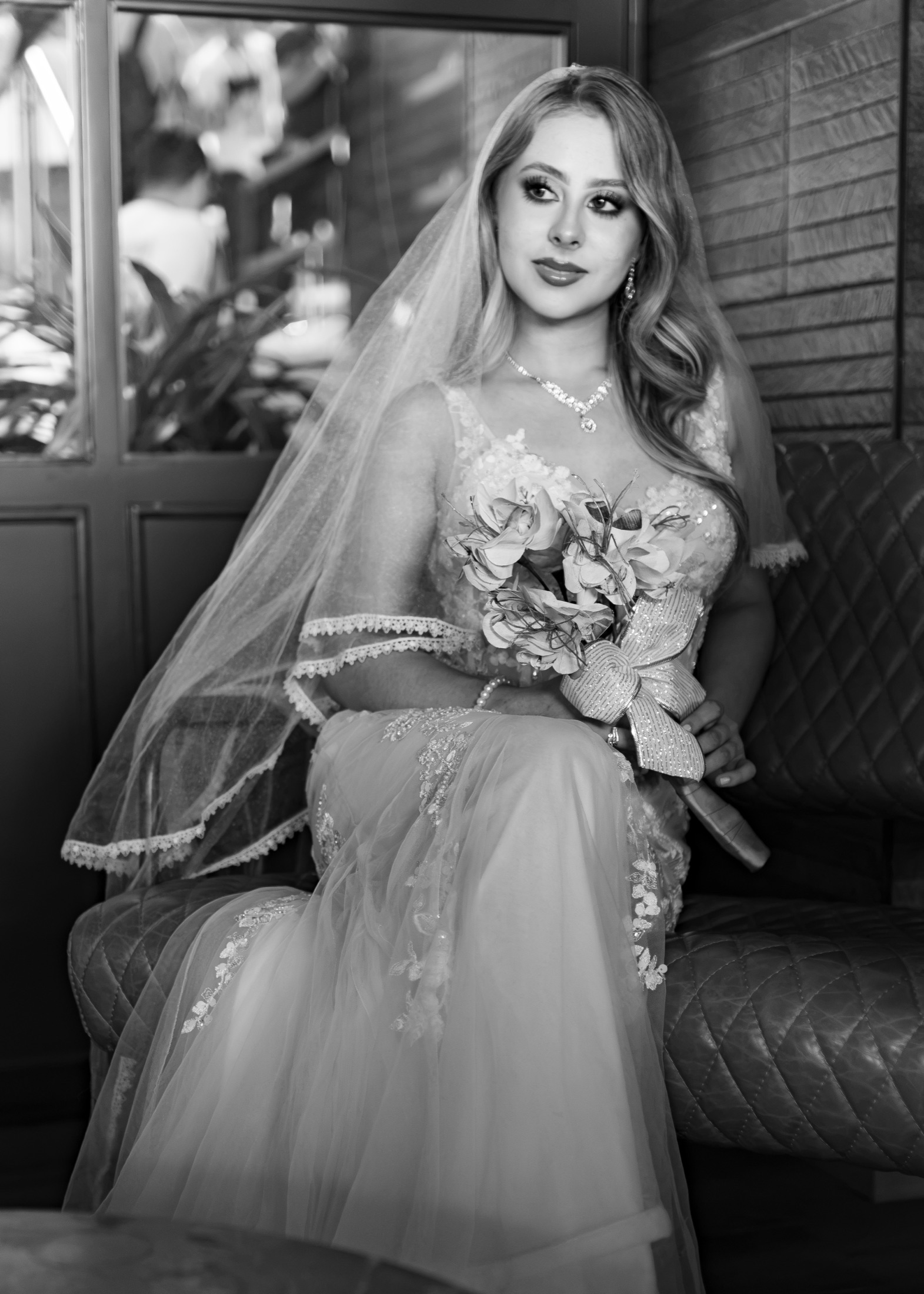 Novia sentada con velo y ramo de flores en blanco y negro