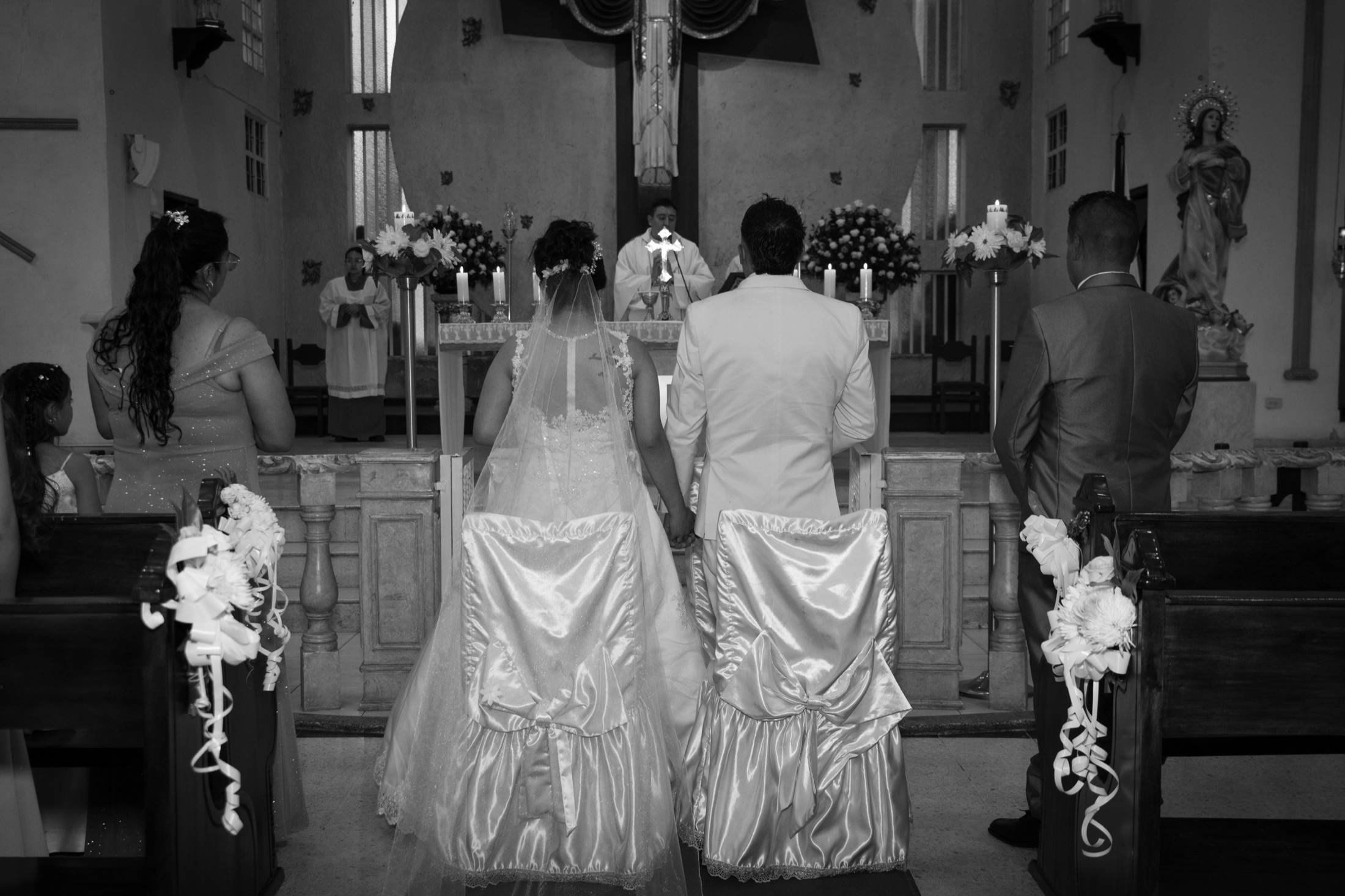 Novios de espaldas tomados de la mano frente al altar de una iglesia
